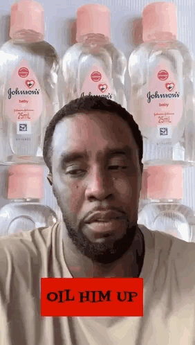 A Man Is Standing In Front Of A Row Of Johnson 'S Baby Oil Bottles . GIF