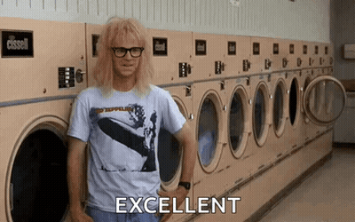 A Man Is Standing In Front Of A Row Of Washing Machines In A Laundromat And Says Excellent . GIF