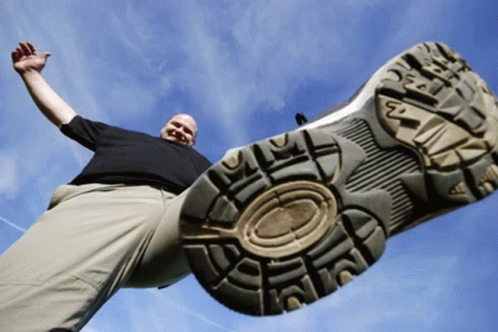 A Man Is Standing In Front Of A Shoe With The Letter N On The Sole GIF
