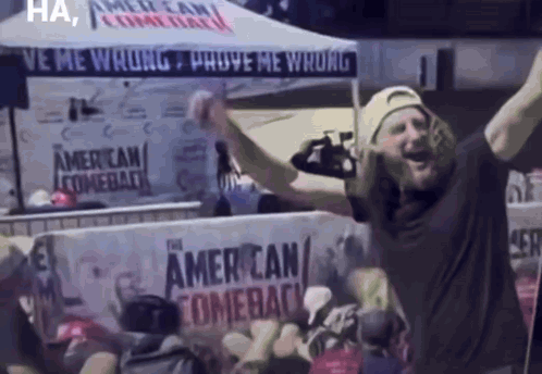 A Man Is Standing In Front Of A Sign That Says American Comeback GIF