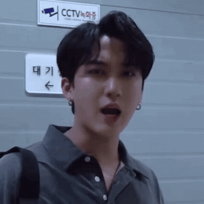 A Man Is Standing In Front Of A Sign That Says Cctv On It . GIF