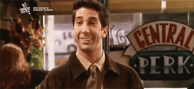 A Man Is Standing In Front Of A Sign That Says Central Perk GIF