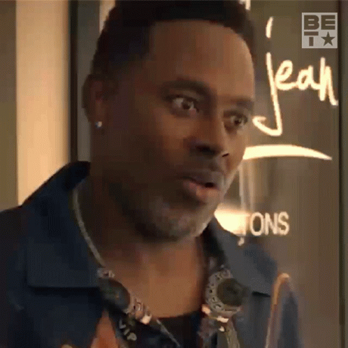 A Man Is Standing In Front Of A Sign That Says Jean On It GIF