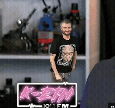 A Man Is Standing In Front Of A Sign That Says K-Eth On It GIF