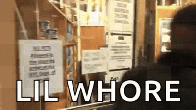 A Man Is Standing In Front Of A Sign That Says Lil Whore GIF