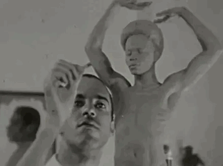 A Man Is Standing In Front Of A Statue Of A Man With His Arms Outstretched . GIF