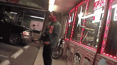 A Man Is Standing In Front Of A Store That Says Rockstar Energy Drink GIF