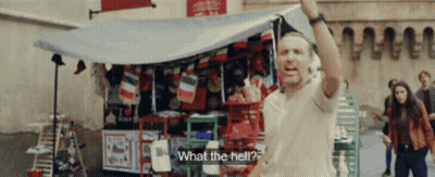 A Man Is Standing In Front Of A Store With A Sign That Says " What The Hell " GIF
