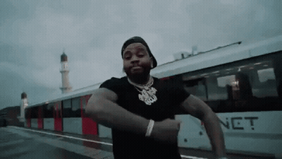 A Man Is Standing In Front Of A Train And Dancing . GIF