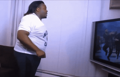 A Man Is Standing In Front Of A Tv And Wearing A White Shirt That Says Nyc GIF