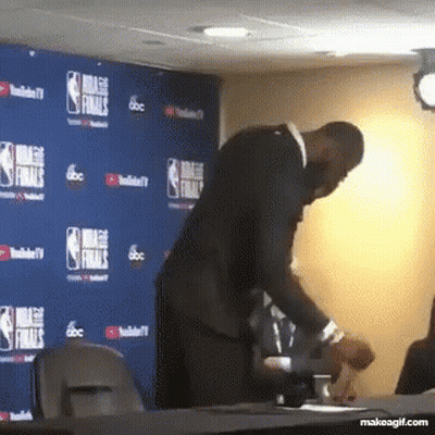 A Man Is Standing In Front Of A Wall That Says Nba Finals On It GIF