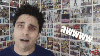 A Man Is Standing In Front Of A Wall With A Bunch Of Pictures On It And Says Awww GIF