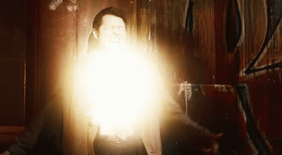 A Man Is Standing In Front Of A Wall With A Light Coming Out Of His Chest . GIF