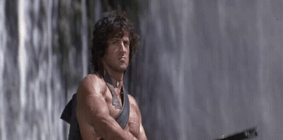 A Man Is Standing In Front Of A Waterfall With His Arms Crossed . GIF