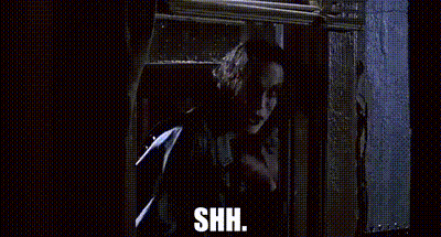 A Man Is Standing In Front Of A Window And Holding A Gun . GIF