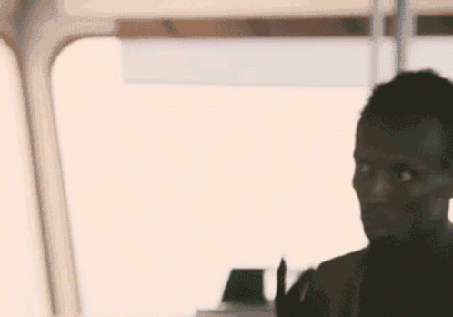 A Man Is Standing In Front Of A Window And Looking At Something . GIF