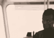 A Man Is Standing In Front Of A Window With The Words `` Look At Me '' Written On It . GIF