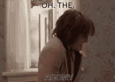 A Man Is Standing In Front Of A Window With The Words " Oh The Agony " Written On The Screen . GIF