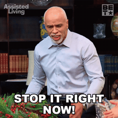 A Man Is Standing In Front Of A Wreath And Says Stop It Right Now GIF