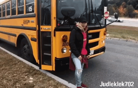 A Man Is Standing In Front Of A Yellow School Bus With The Number 15 On It GIF