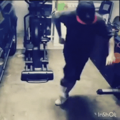 A Man Is Standing In Front Of An Elliptical Machine In A Garage . GIF