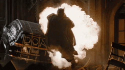 A Man Is Standing In Front Of An Explosion With The Letter D On It GIF
