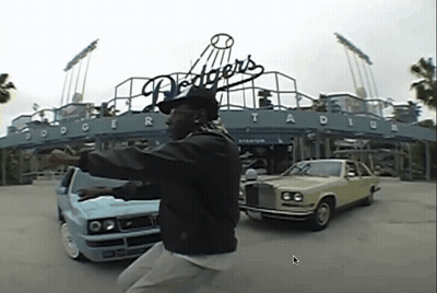 A Man Is Standing In Front Of Dodgers Stadium GIF