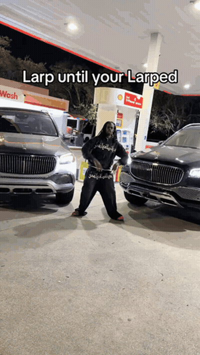A Man Is Standing In Front Of Two Cars At A Gas Station With A Caption That Says Larp Until Your Larped GIF