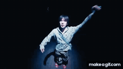 A Man Is Standing In The Dark With His Arms In The Air .. GIF