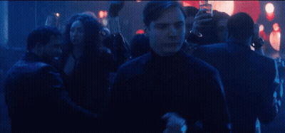 A Man Is Standing In The Middle Of A Crowd Of People Dancing In A Club . GIF