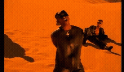 A Man Is Standing In The Middle Of A Desert In Front Of An Orange Background . GIF