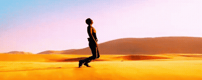 A Man Is Standing In The Middle Of A Desert Looking Up At The Sky . GIF
