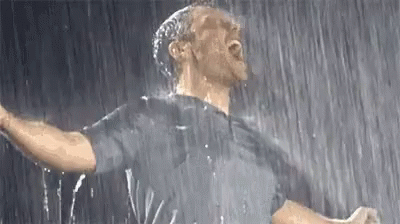 A Man Is Standing In The Rain With His Mouth Open . GIF