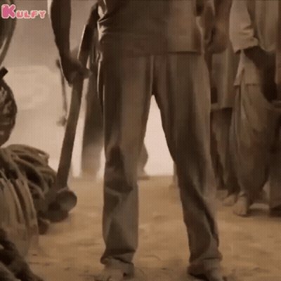 A Man Is Standing In The Sand Holding A Sword In His Hand . GIF