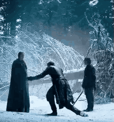 A Man Is Standing In The Snow Holding A Sword While Another Man Looks On . GIF