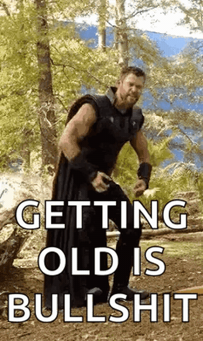 A Man Is Standing In The Woods With The Words `` Getting Old Is Bullshit '' . GIF