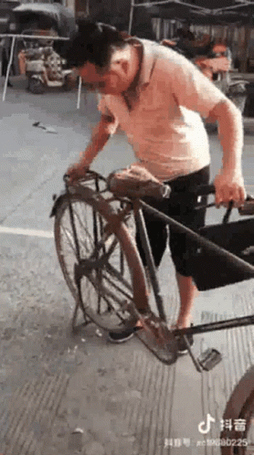 A Man Is Standing Next To A Bicycle On A Sidewalk . GIF