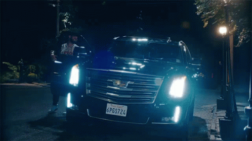 A Man Is Standing Next To A Black Cadillac With A California License Plate GIF