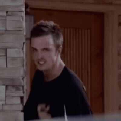 A Man Is Standing Next To A Brick Wall And Making A Funny Face With His Finger In His Mouth . GIF
