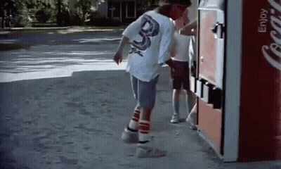 A Man Is Standing Next To A Coca Cola Vending Machine On The Sidewalk . GIF