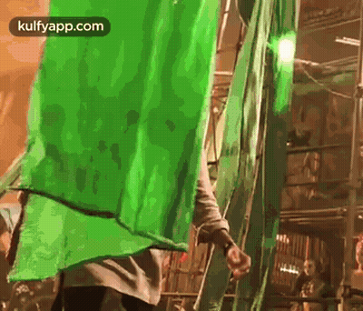 A Man Is Standing Next To A Ladder With A Green Screen Behind Him . GIF