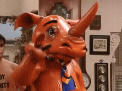 A Man Is Standing Next To A Rhino Mascot Costume In A Living Room . GIF
