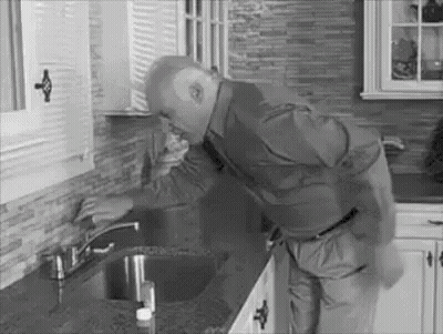 A Man Is Standing Next To A Sink In A Kitchen . GIF