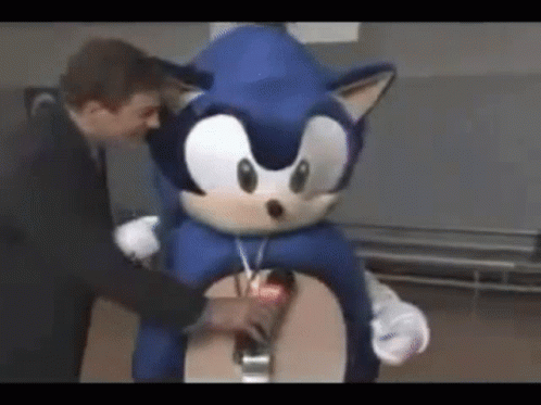 A Man Is Standing Next To A Sonic The Hedgehog Costume GIF
