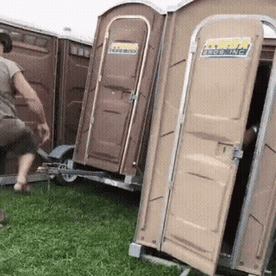 A Man Is Standing Next To A Trailer With Portable Toilets Attached To It And One Of Them Is Open GIF
