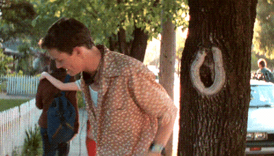 A Man Is Standing Next To A Tree With A Horseshoe Shaped Hole In It GIF