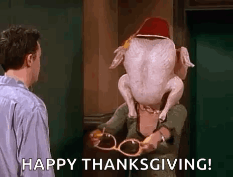 A Man Is Standing Next To A Woman Holding A Turkey With A Hat On Its Head . GIF
