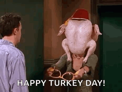 A Man Is Standing Next To A Woman Holding A Turkey With A Hat On Its Head . GIF