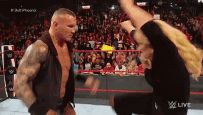 A Man Is Standing Next To A Woman In A Wrestling Ring . GIF