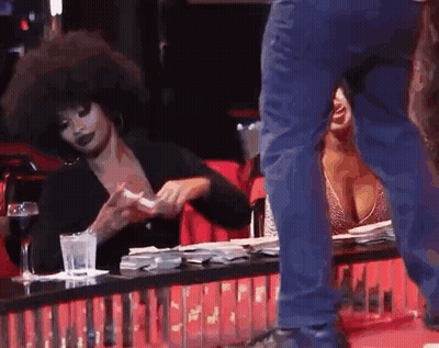 A Man Is Standing Next To A Woman Sitting At A Table . GIF